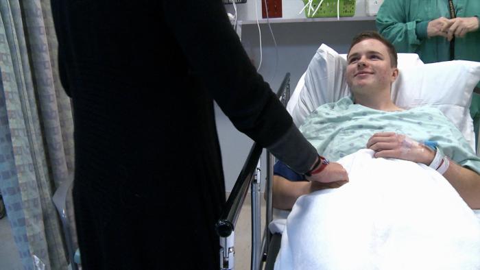 Real Boy Movie: Bennett smiling from a hospital bed, smiling up at an adult in a black suit