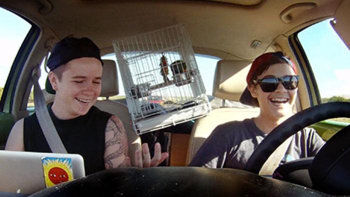 Real Boy Movie: Bennett & Dylan smiling, laughing in a car with birdcage in between them