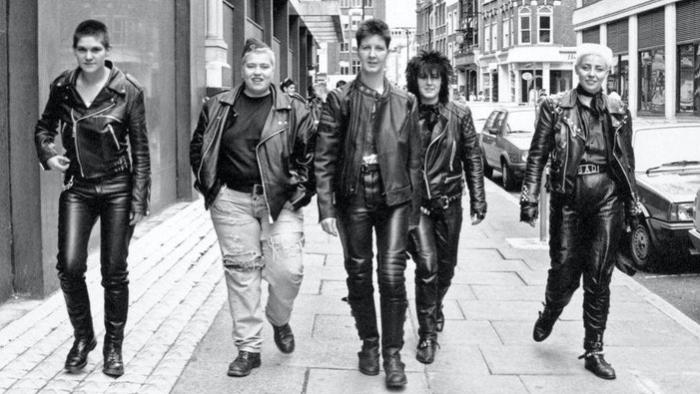 Rebel Dykes: Black and white image of five women in leather and denim walking down a London street.