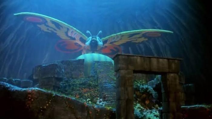 Rebirth of Mothra Movie: Large moth with vibrant wings rests on ancient ruins underwater.