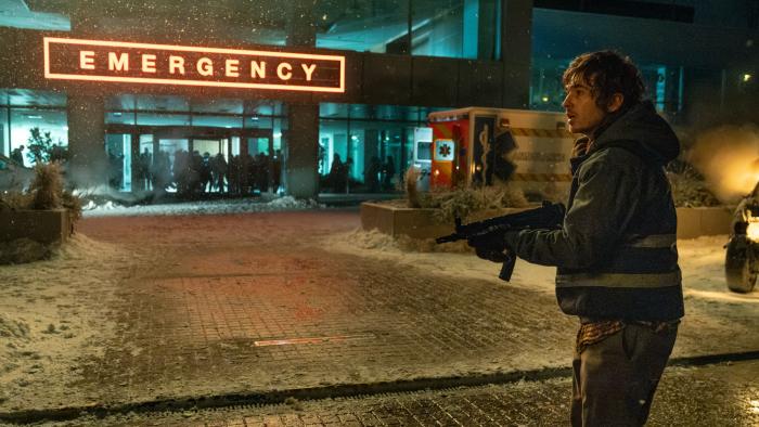 Resident Evil Movie: Bryan, holding a powerful rifle, pauses in front of a hospital, the lobby overrun by monsters