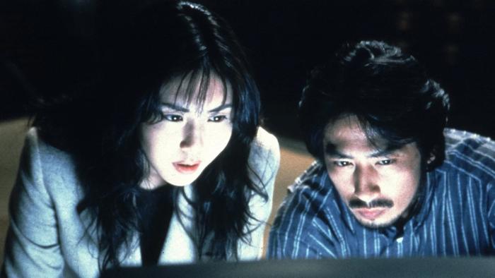 The Ring: A Japanese woman and man intently focus on a screen in a dimly-lit room