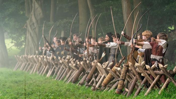 Robin and the Hoods: A group of kids stand in line wearing Medieval costumes and holding bows and arrows