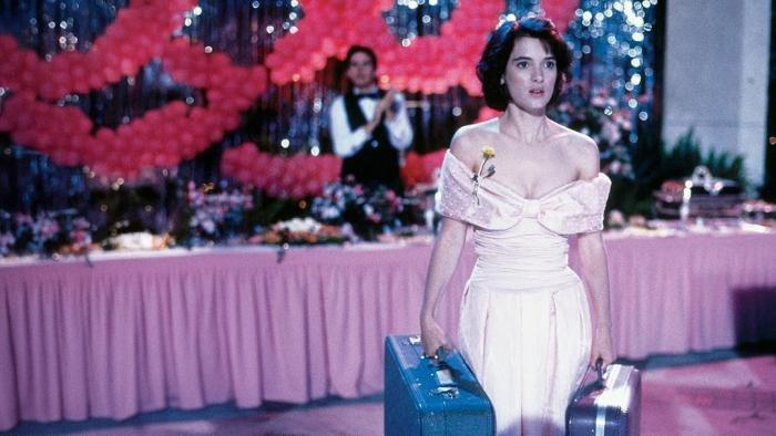 Welcome Home, Roxy Carmichael: Woman in a pink dress holding suitcases at a decorated community hall