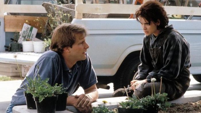 Welcome Home, Roxy Carmichael: Man kneeling by plants talking to seated teenage girl near a truck