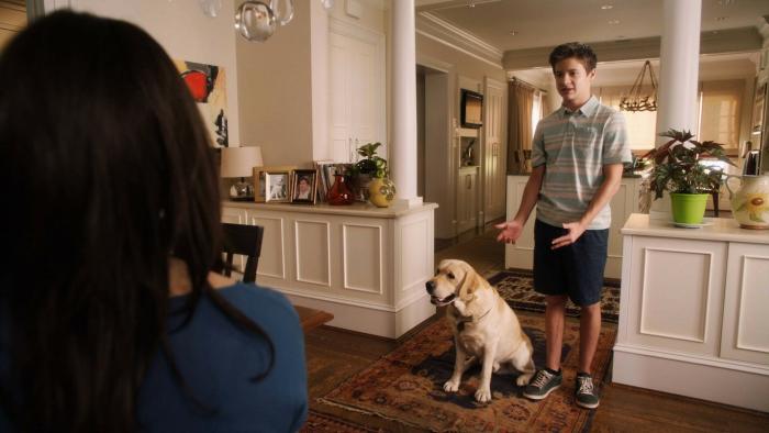 Rufus 2: A young White boy stands in his house and gestures to his dog, the back of his mom's head can be seen in front of him