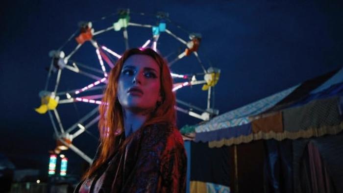 Rumble Through the Dark Movie: Annette (Bella Thorne), with lots of colorful makeup on and standing in front of a Ferris Wheel, has a pensive look on her face