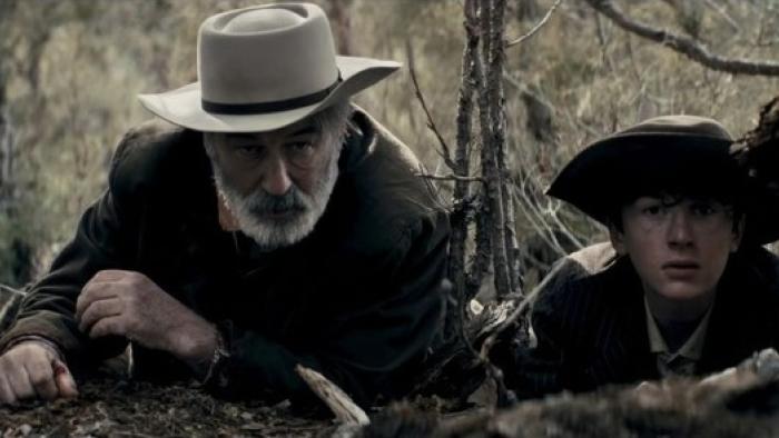 Rust Movie: Rust and Lucas crouch in the brush to observe an approaching threat