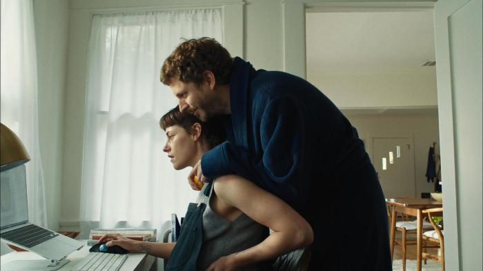 Sacramento movie: Michael Cera cuddles Kristen Stewart while she's sitting at a desk looking at a computer monitor
