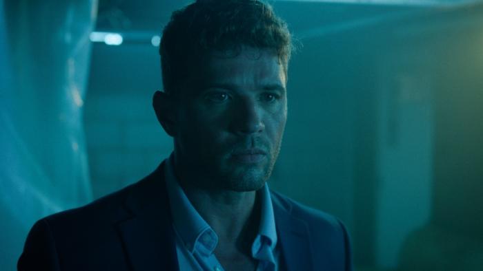 Saint Clare Movie: In a dimly lit room, Detective Rich Timmons (Ryan Phillippe) has a worried look on his face