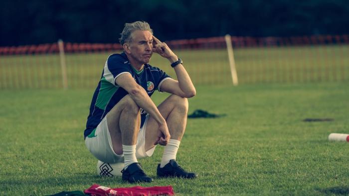 Saipan: Mick McCarthy sitting down on a soccer ball on a soccer pitch thinking