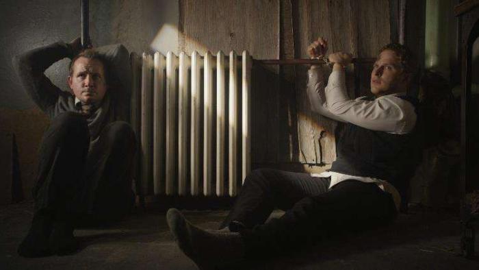The Saratov Approach Movie: Tuttle (Corbin Allred, left) and Propst (Maclain Nelson) and are tied to a radiator by their hands