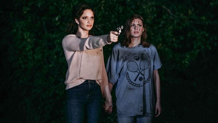 Satanic Panic Movie: Judi holds a gun standing next to Sam