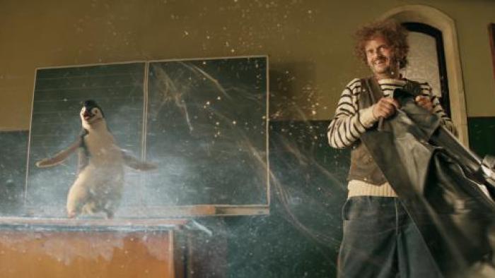 School of Magical Animals 2: A penguin stands on a school desk while a man stands next to him
