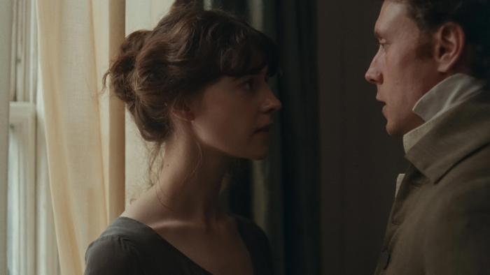 Sense and Sensibility: A young woman and a man stare into each others eyes intensely, near a curtained window