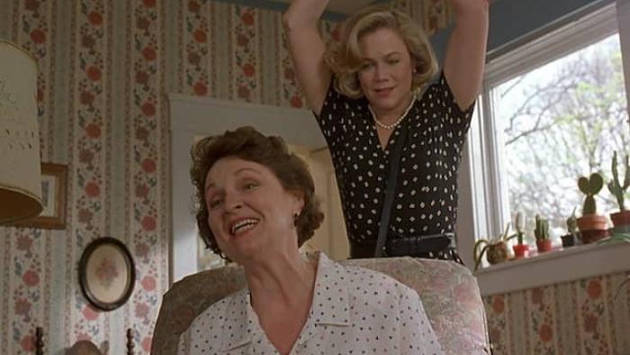 Serial Mom Movie: A mom holds up her arms while sneaking up behind an older woman, as if to stab her in the back