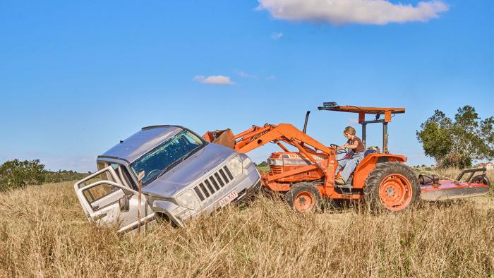 Seven Snipers: Orange tractor pulling a silver SUV from a field under a blue sky