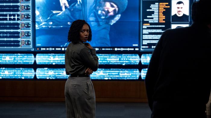 Shelter movie: Naomi Ackie stands in a law enforcement communications center in front of a screen with Jason Statham on it