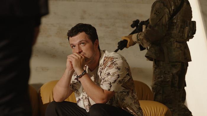 Signal One movie: Josh Hutcherson sits with his hands clasped against his mouth as a machine gun is pointed at him