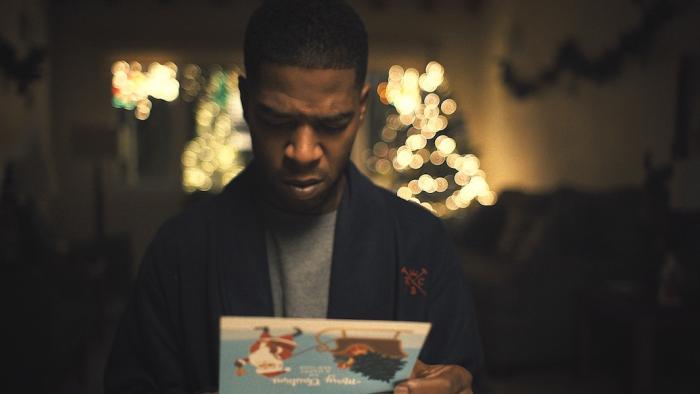 Silent Night Movie: Police detective Dennis Vassel (Scott "Kid Cudi" Mescudi) looks concerned as he reads a mysterious Christmas card