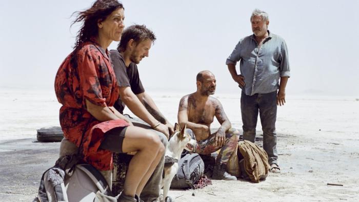Sirāt: Ravers sitting on rocks in dessert.