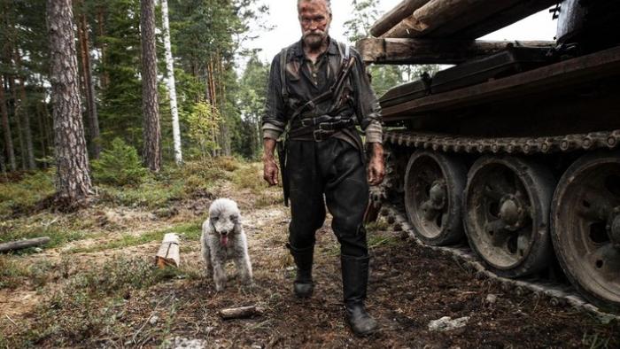 Sisu: Road to Revenge Movie: Standing near a military tank with his faithful dog, Ukko, Aatami Korpi formulates a plan