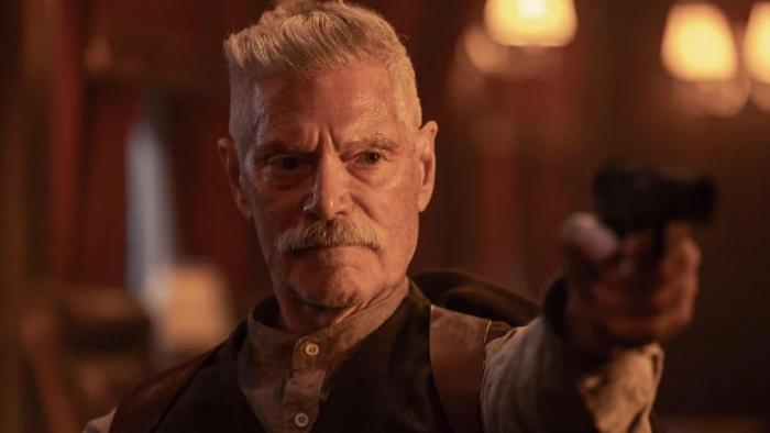 Sisu: Road to Revenge Movie: Draganov (Stephen Lang) grimly points a gun at someone out of frame