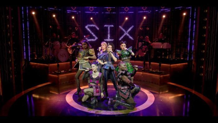 Six the Musical Live! movie: The six wives of Henry VIII pose in a circle on stage