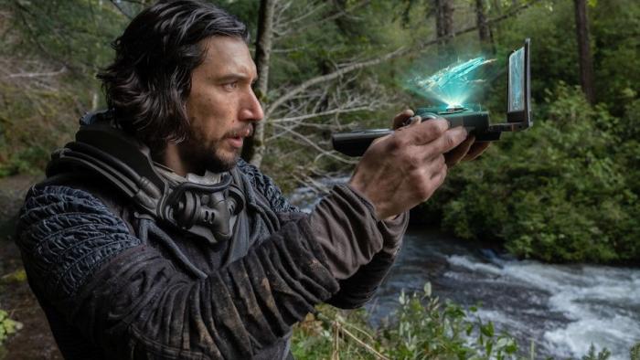 65 Movie: Adam Driver holds a space-age device and examines the 3D readout
