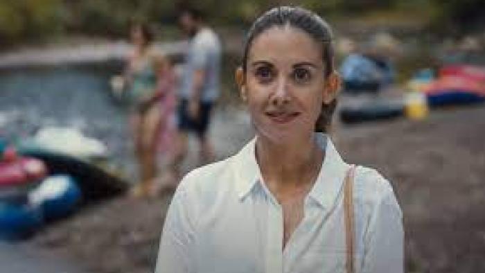 omebody I Used to Know: A woman in a white shirt smiles while outdoors.