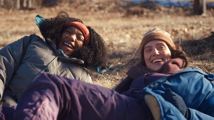 Sorry, Baby movie: Lydie (Naomi Ackie) and Agnes (Eva Victor) laugh while lying in a field