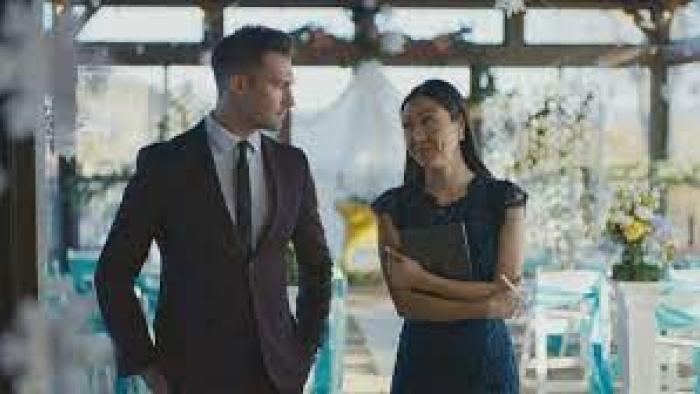 Stars Fell Again Movie: James Maslow wears a suit at a wedding while looking a woman holding a clipboard