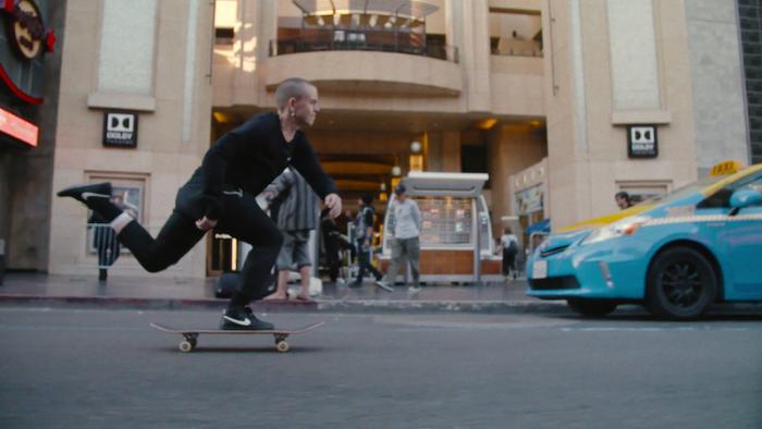 Skateboard pro Leo Baker skateboarding down street.