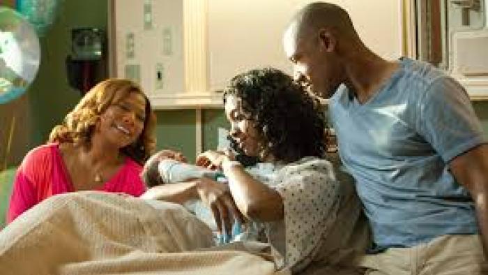 Steel Magnolias: Woman holding baby in hospital bed, two people beside her smiling.