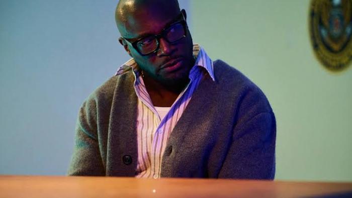 Stepfather Movie: Taye Diggs with glasses and sweater, seated in dimly lit room.