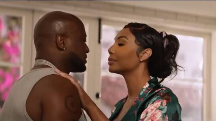 Stepfather Movie: Black couple embracing in a brightly lit room, window with pink flowers in the background.