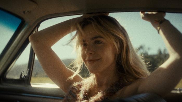 Stone Cold Fox movie: Kiernan Shipka sits in a car, smiling with her arms up and outside of the window