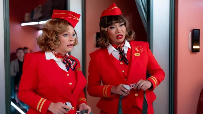 Stop! That! Train! movie: Two attendants in red uniforms stand in a train aisle
