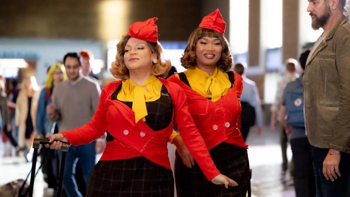 Stop! That! Train! movie: Two women in matching red and yellow outfits walk confidently in a busy station