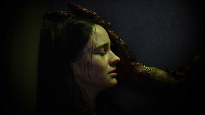 Stopmotion Movie: Ella (Aisling Franciosi), seen from the side, closes her eyes as a huge, monstrous hand caresses her face