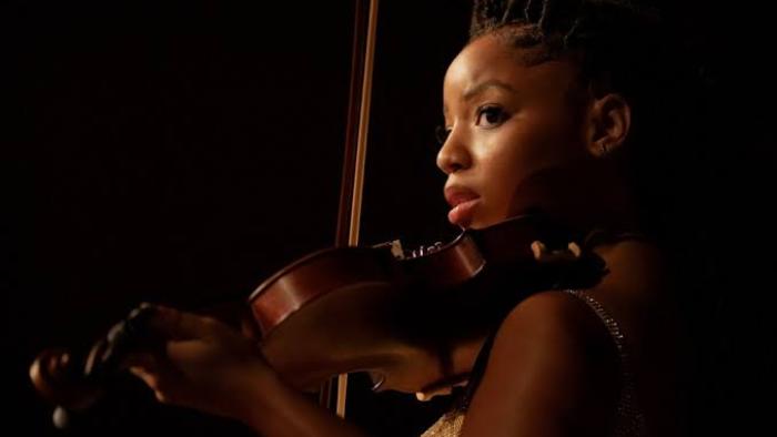 Strung: Chloe Bailey playing violin under soft lighting.