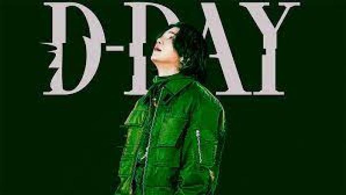 Suga: Road to D-Day: Suga stands in green against "D-Day" background
