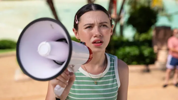 Summer's Last Resort: Summer looks pained while using a megaphone in front of a tropical background.