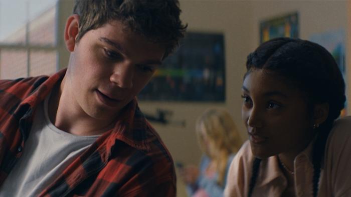 Supercell Movie: A teen boy is leaning back to talk to teen girl who sits behind him in class