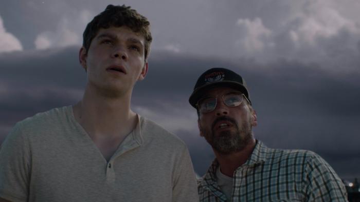 Supercell Movie: A teen boy and his father look up at the sky while a storm is brewing behind them