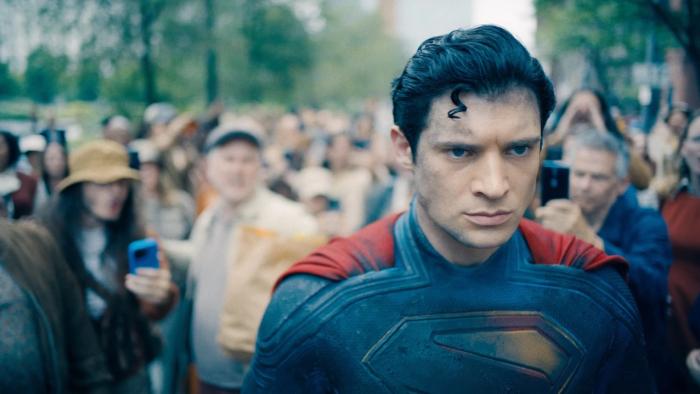 Superman movie: Superman, his back turned to a large crowd, looks very serious