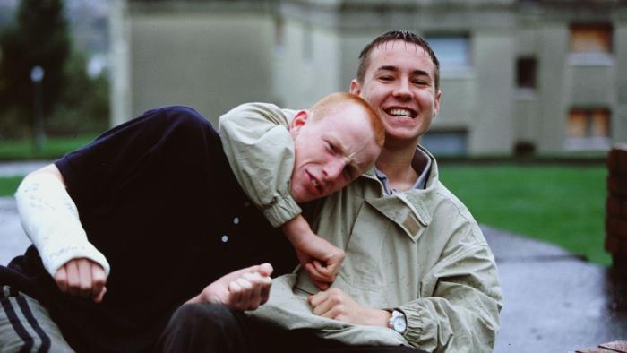 Sweet Sixteen: A young White male teen smiles as he gets his friend in a playful headlock