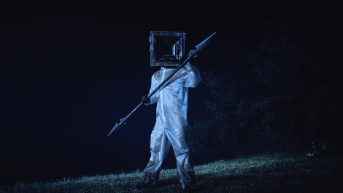 Teenage Sex and Death at Camp Miasma movie: Camp Miasma killer Little Death wears a vent mask and holds a spear on a lawn