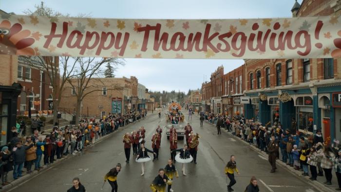 Thanksgiving Movie: A Thanksgiving parade is underway, seen from just above the middle of the street