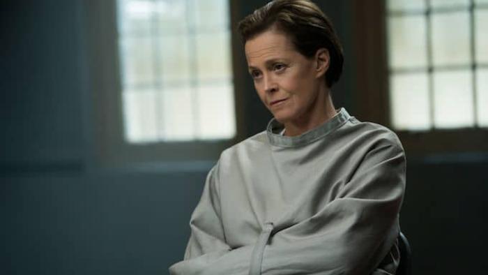The Assignment Movie: Sigourney Weaver sits indoors wearing a straitjacket.